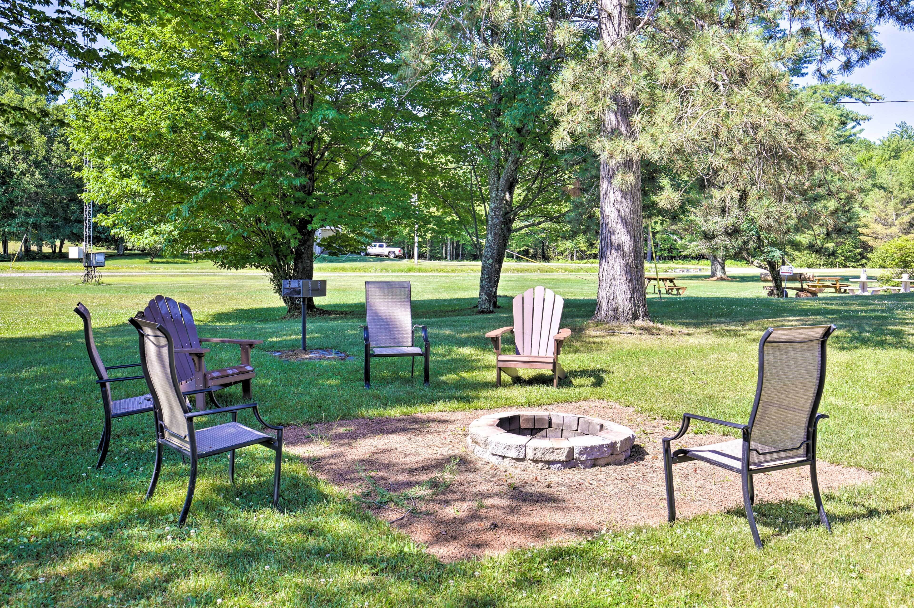 A park with several Adirondack chairs and a fire pit.