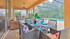 Un espace extérieur aménagé avec des meubles en osier, une table en verre et une vue sur une piscine.