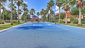 Un terrain de basket entouré de palmiers et surmonté d’un pavillon au toit bleu.
