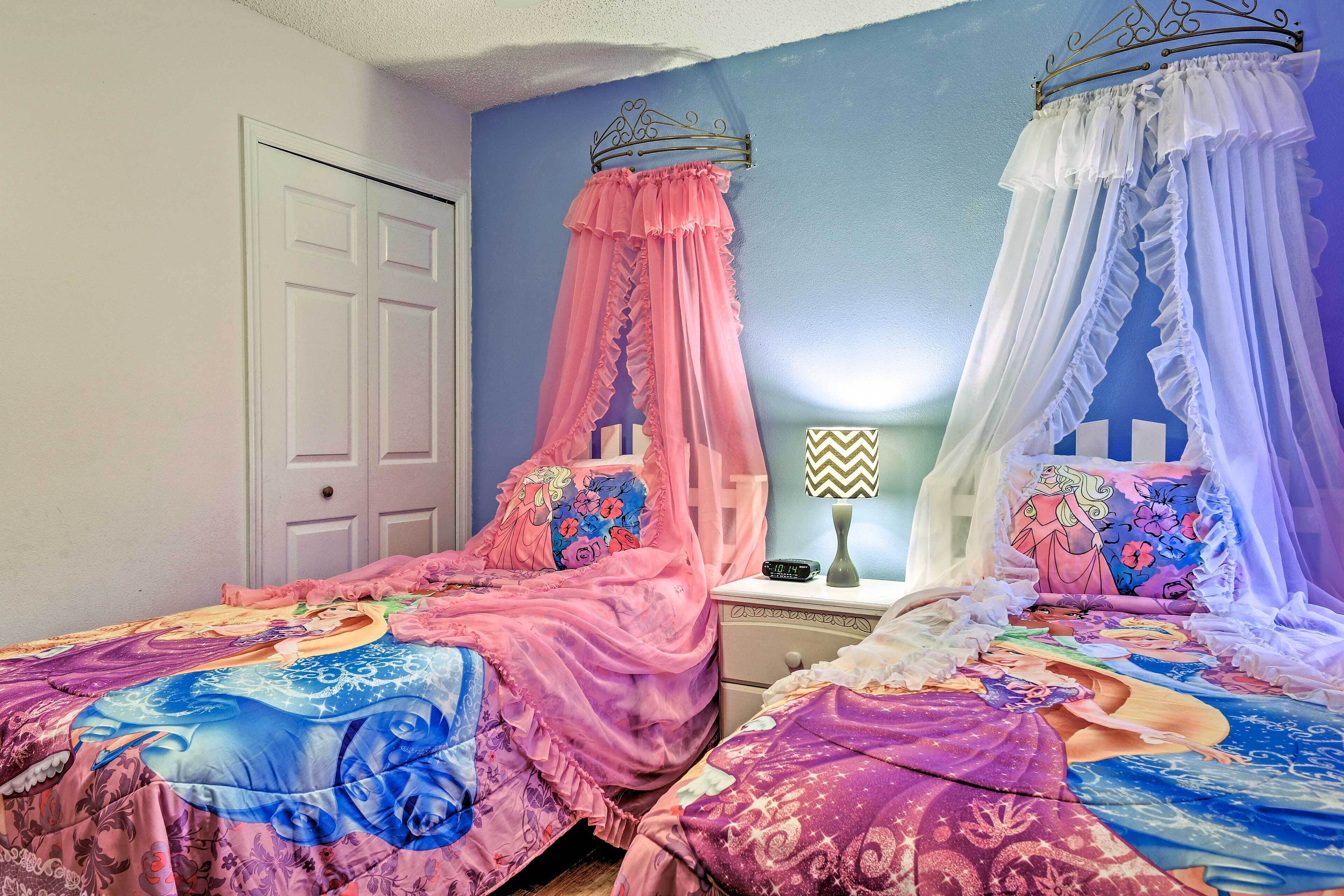 Une chambre à coucher avec deux lits, chacun étant agrémenté d’un couvre-lit à baldaquin et de coussins assortis.