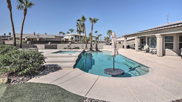 A swimming pool with a hot tub, surrounded by palm trees and a patio area with outdoor furniture. - Putting Green & Bbq: Modern Lake Havasu Oasis! (Lake Havasu City)