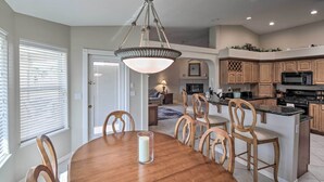 A modern kitchen with wooden cabinets, a central island, and a dining area with a wooden table and chairs. - Putting Green & Bbq: Modern Lake Havasu Oasis! (Lake Havasu City)