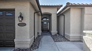 A building with a stone facade, a dark garage door, and a pathway leading to a dark entrance door. - Putting Green & Bbq: Modern Lake Havasu Oasis! (Lake Havasu City)