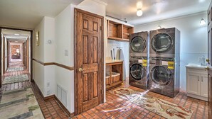 A laundry room with two stainless steel front-loading washers and dryers, a white sink, and a wooden door. - Spacious Arizona Home, 6 Mi to Old Town Scottsdale (Paradise Valley)