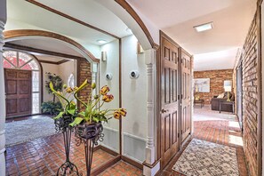A hallway with a brick floor, a white door, and a potted plant with yellow flowers. - Spacious Arizona Home, 6 Mi to Old Town Scottsdale (Paradise Valley)