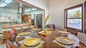 A dining area with a round table set for six, surrounded by wooden chairs. A large mirror reflects the kitchen area. - Spacious Arizona Home, 6 Mi to Old Town Scottsdale (Paradise Valley)