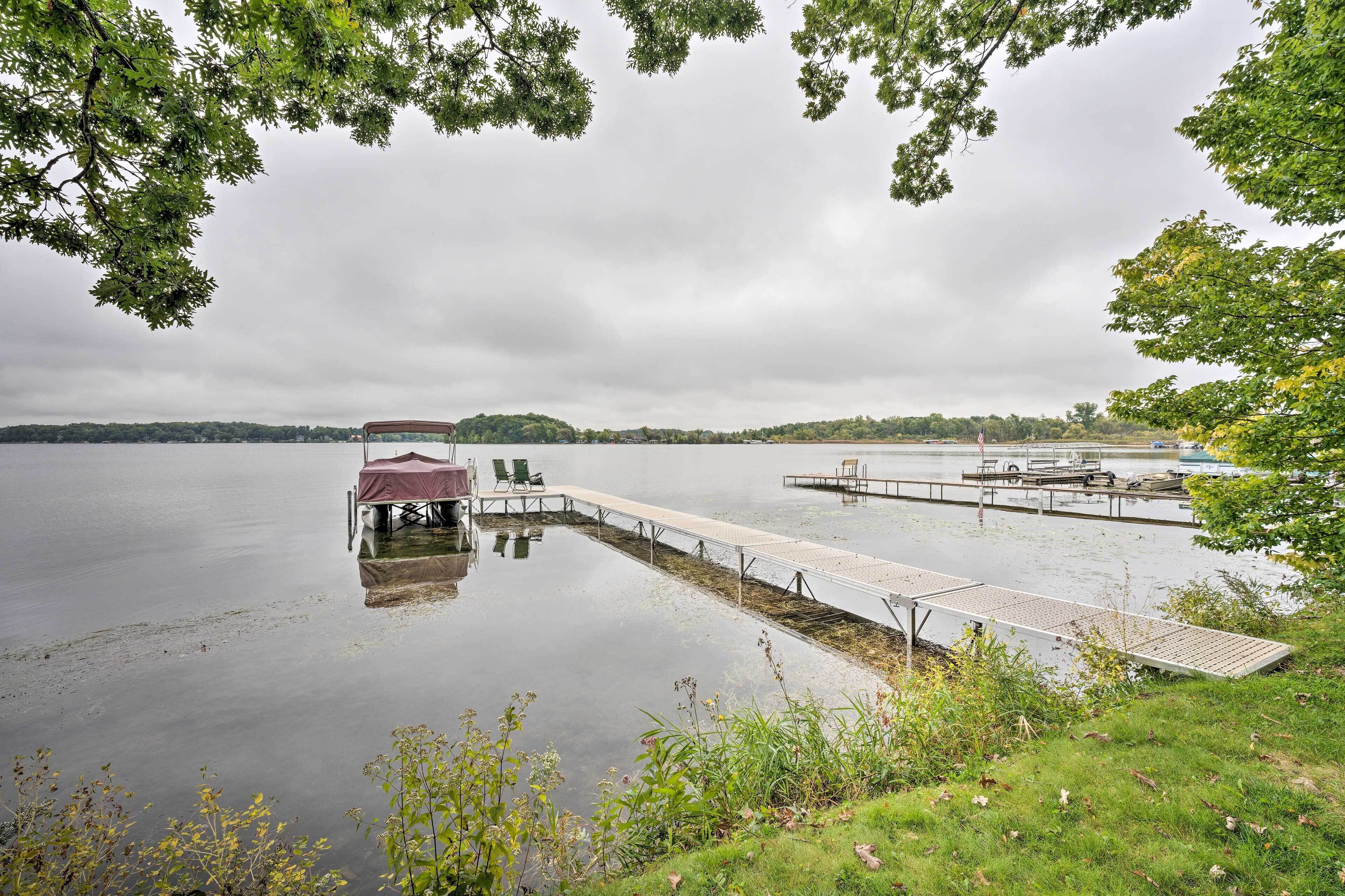A lakeside dock with a covered seating area and a boat launch ramp.