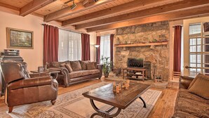 A cozy living room with a stone fireplace, leather furniture, and a wooden ceiling. - Tranquil Smoky Mountain Cabin w/ Porch & Fire Pit (Newport)