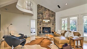 A spacious living room with a stone fireplace, leather furniture, and a large window.