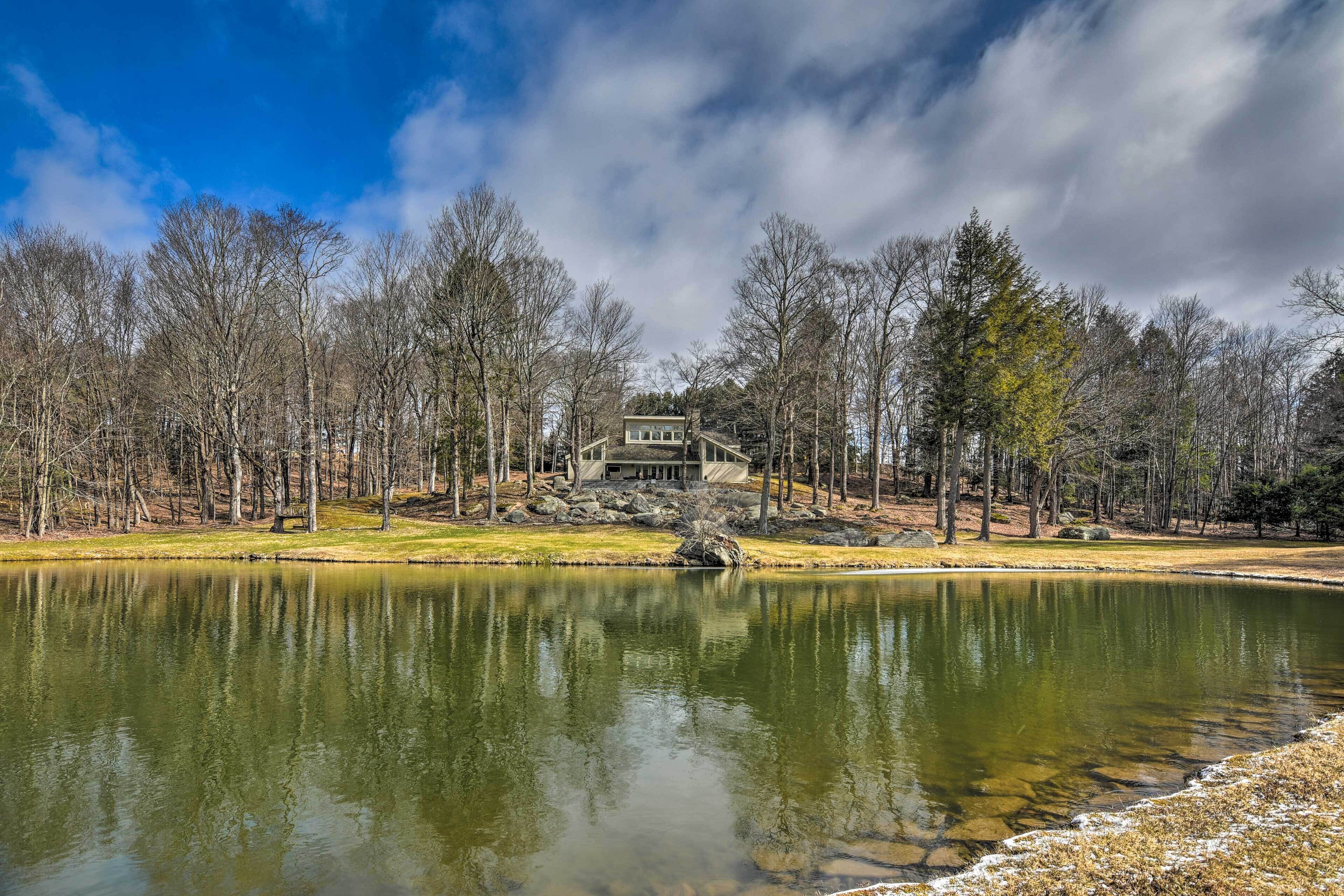 Une vue sur le lac, avec une maison située sur une colline, entourée d’arbres.