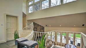 A spacious indoor area with a staircase, a seating area with a cushioned bench, and a potted plant.