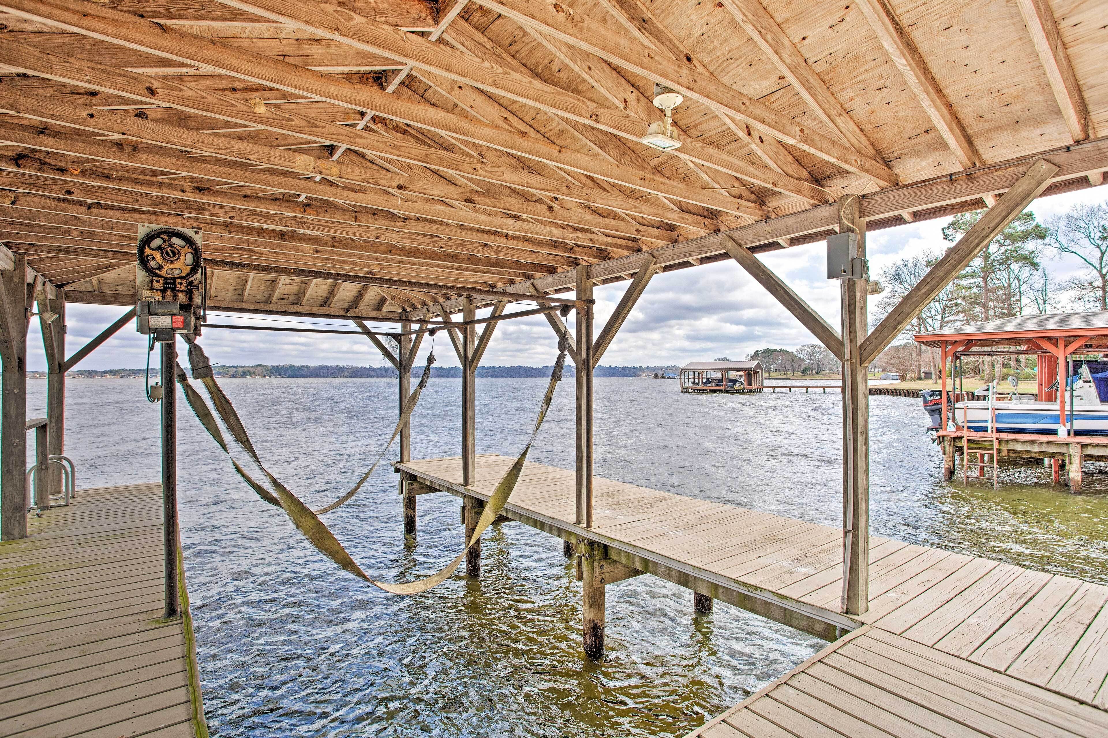 A wooden pier with a covered area, a boat docked on the right, and a water body in the background.