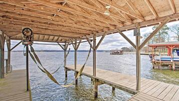 A wooden pier with a covered area, a boat docked on the right, and a water body in the background.