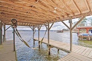 Een houten steiger met een overdekt gedeelte, een boot afgemeerd aan de rechterkant en een waterlichaam op de achtergrond.