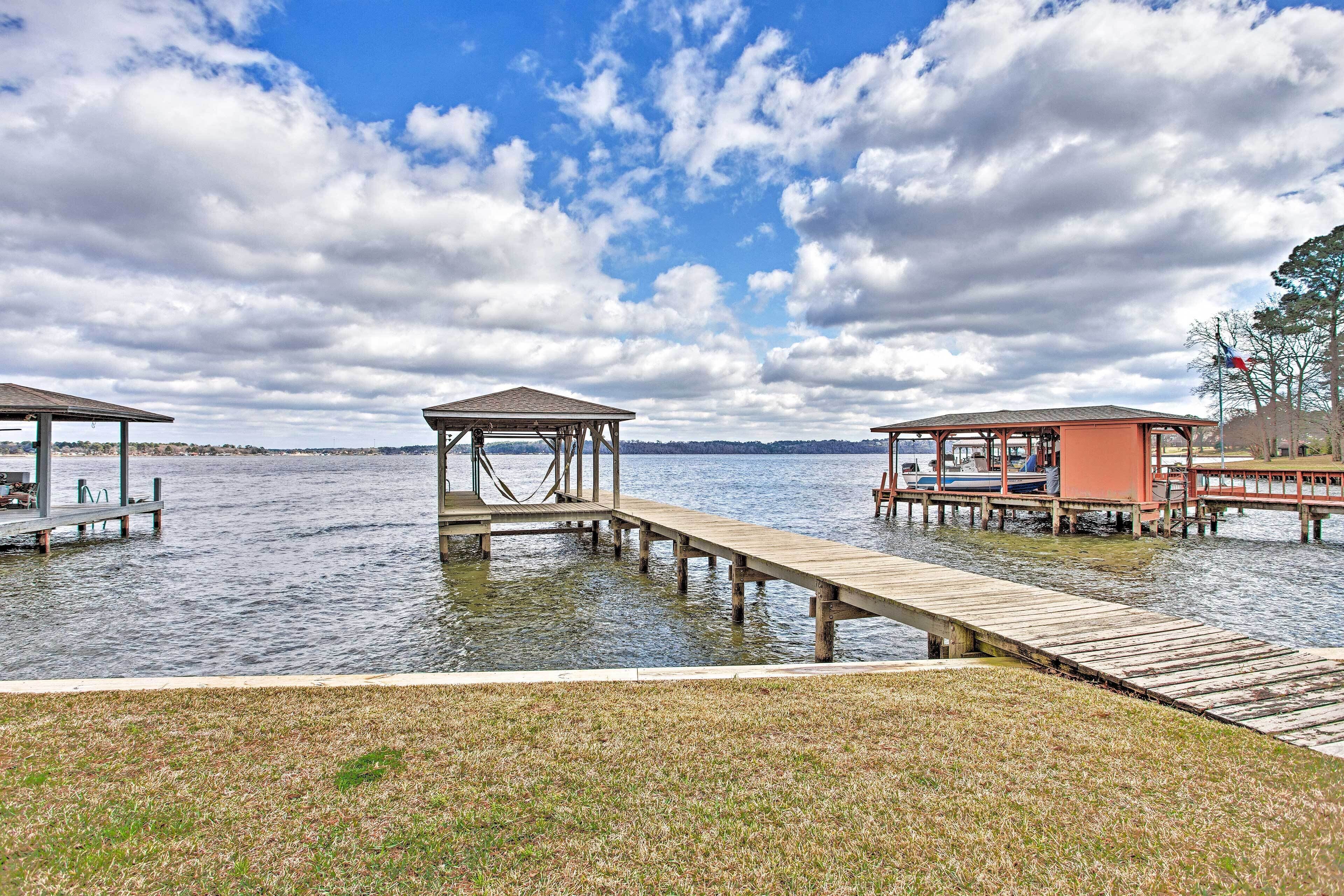 A lakeside dock with wooden structures, including a gazebo and a covered area, connected by a wooden walkway.