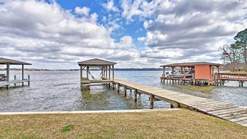 A lakeside dock with wooden structures, including a gazebo and a covered area, connected by a wooden walkway.