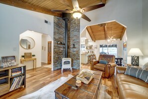 A spacious living room with a fireplace, a leather sofa, a coffee table, and a dining area visible through an open archway.