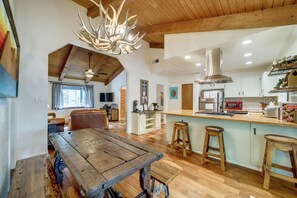 A spacious kitchen with wooden flooring, a central island, and a modern stainless steel range hood. - Hot Tub & Patio: Pet-friendly Cabin in Munds Park! (Munds Park)