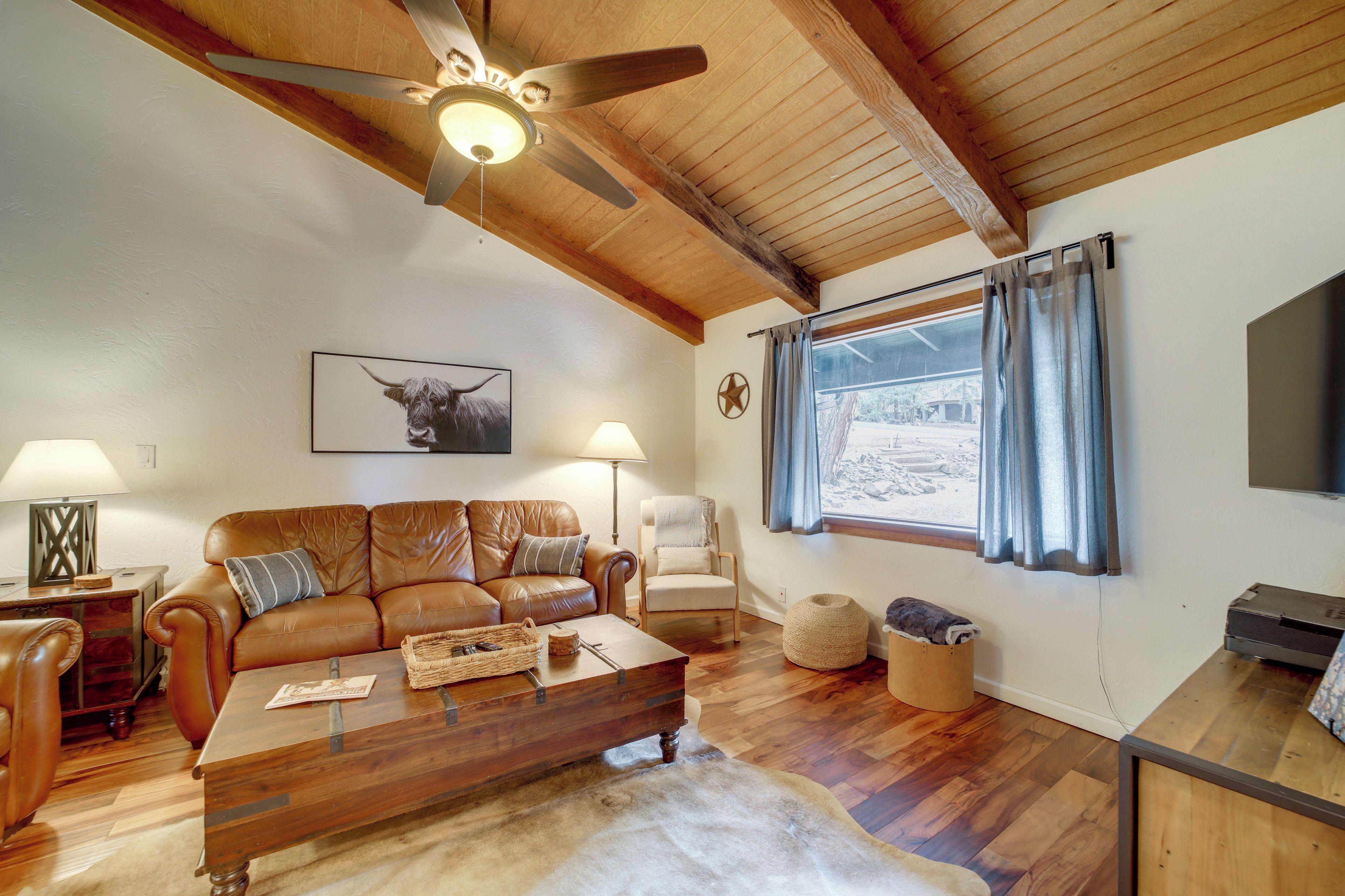 A cozy living room with a brown leather sofa, a wooden coffee table, and a ceiling fan.