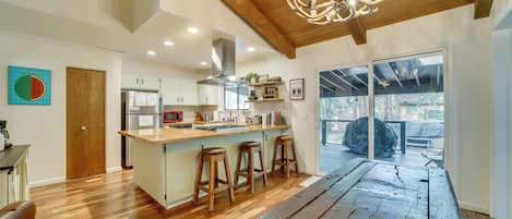 A spacious kitchen with wooden flooring, a central island with stools, and a large dining table.