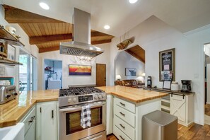A kitchen with a central island, wooden ceiling beams, and a stainless steel range hood. - Hot Tub & Patio: Pet-friendly Cabin in Munds Park! (Munds Park)