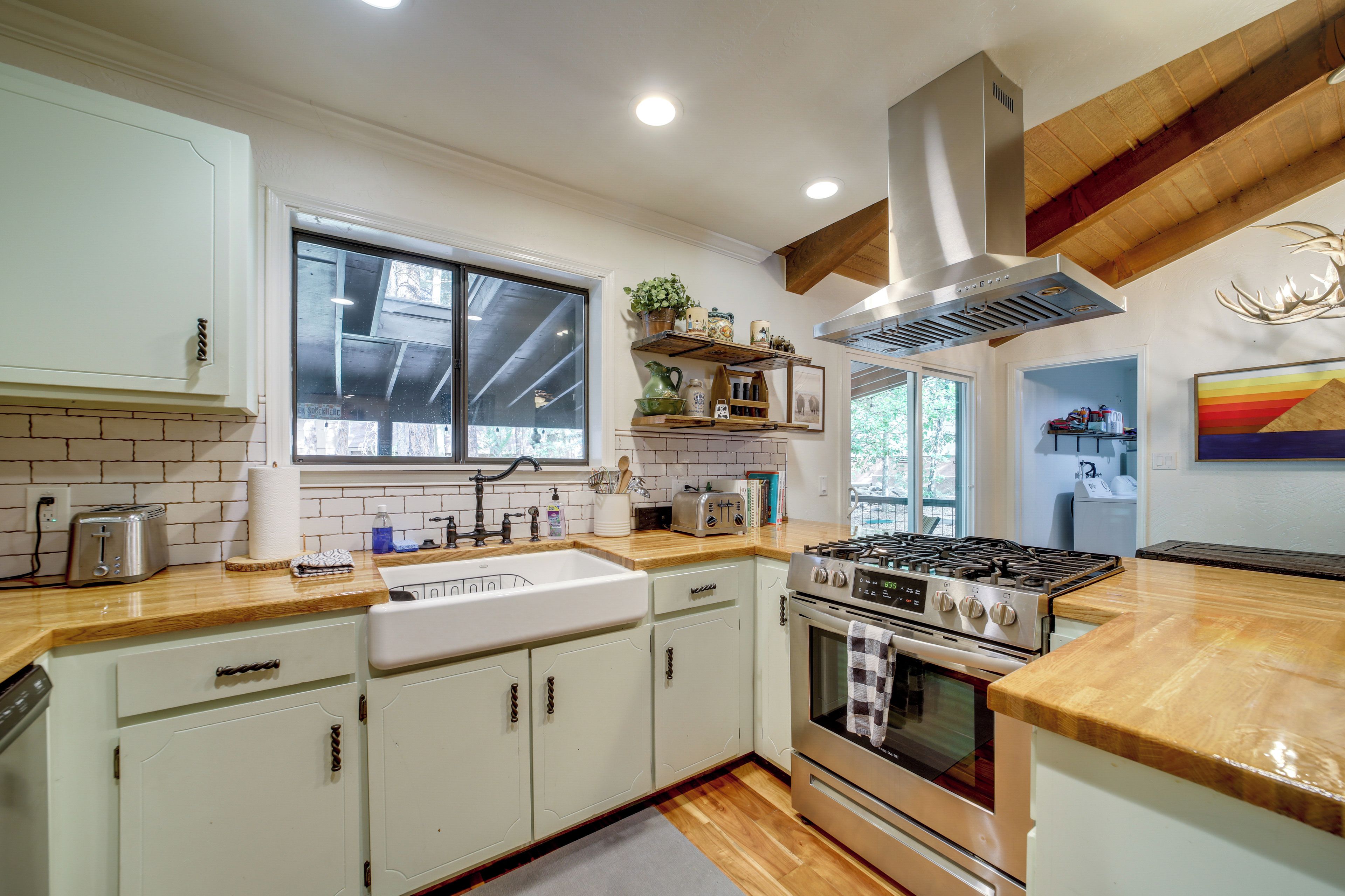 A kitchen with white cabinets, a stainless steel stove, and wooden countertops.