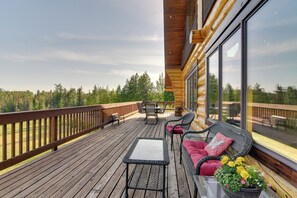 A wooden deck with outdoor furniture, including a table and chairs, and a sofa with cushions. - Legacy Mountain Lodge on 40-acre Ranch w/ Views! (Palmer)