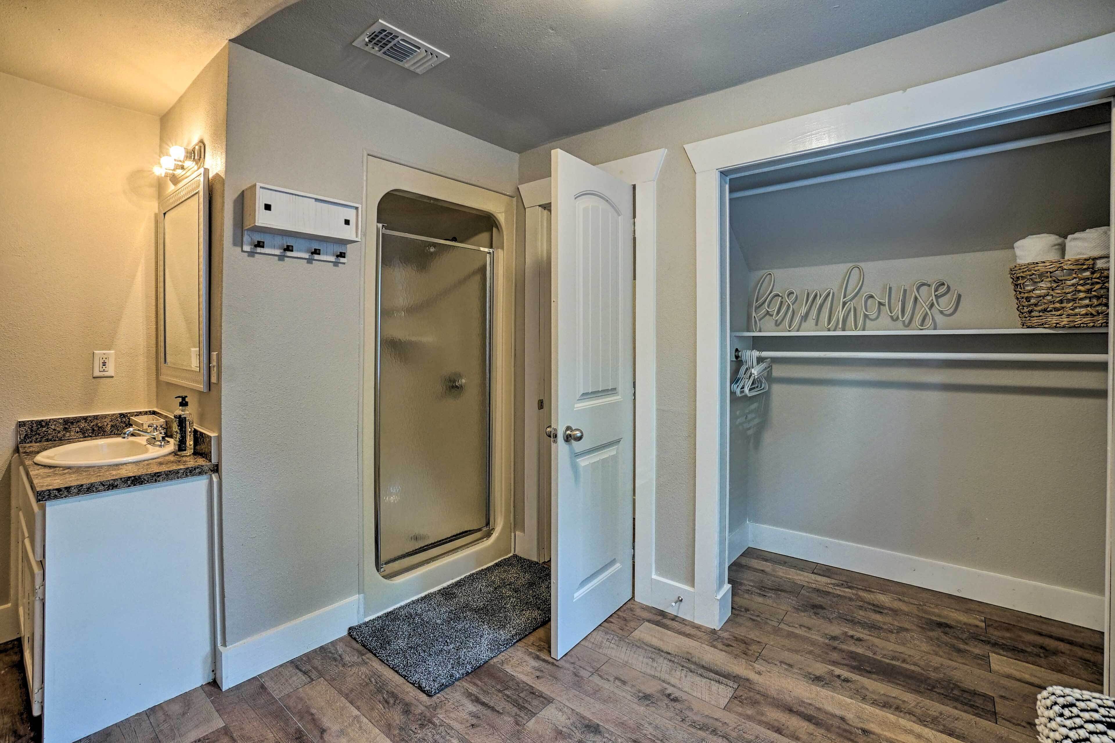 Une salle de bain équipée d’un lavabo, d’un miroir, d’une douche et d’un placard de rangement agrémenté d’une enseigne de style « ferme ».