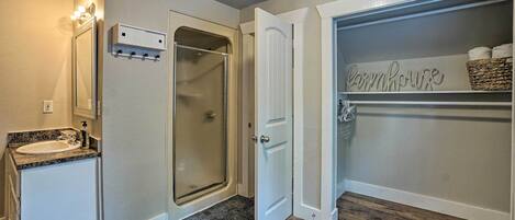 Une salle de bain équipée d’un lavabo, d’un miroir, d’une douche et d’un placard de rangement agrémenté d’une enseigne de style « ferme ».