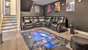 Un salon moderne avec un canapé d’angle, un tapis sur le thème de la galaxie et des affiches de films accrochées au mur.
