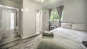 A hotel room with a bed, a ceiling fan, a window with curtains, and a hallway leading to another room. - Serene Smoky Mountain Home w/ Grill & Patio! (Topton)