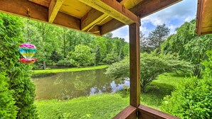 A wooden deck with a view of a pond surrounded by lush greenery. - Serene Smoky Mountain Home w/ Grill & Patio! (Topton)