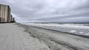 Ein Strand mit sandigem Ufer und einem Gebäude im Hintergrund.
