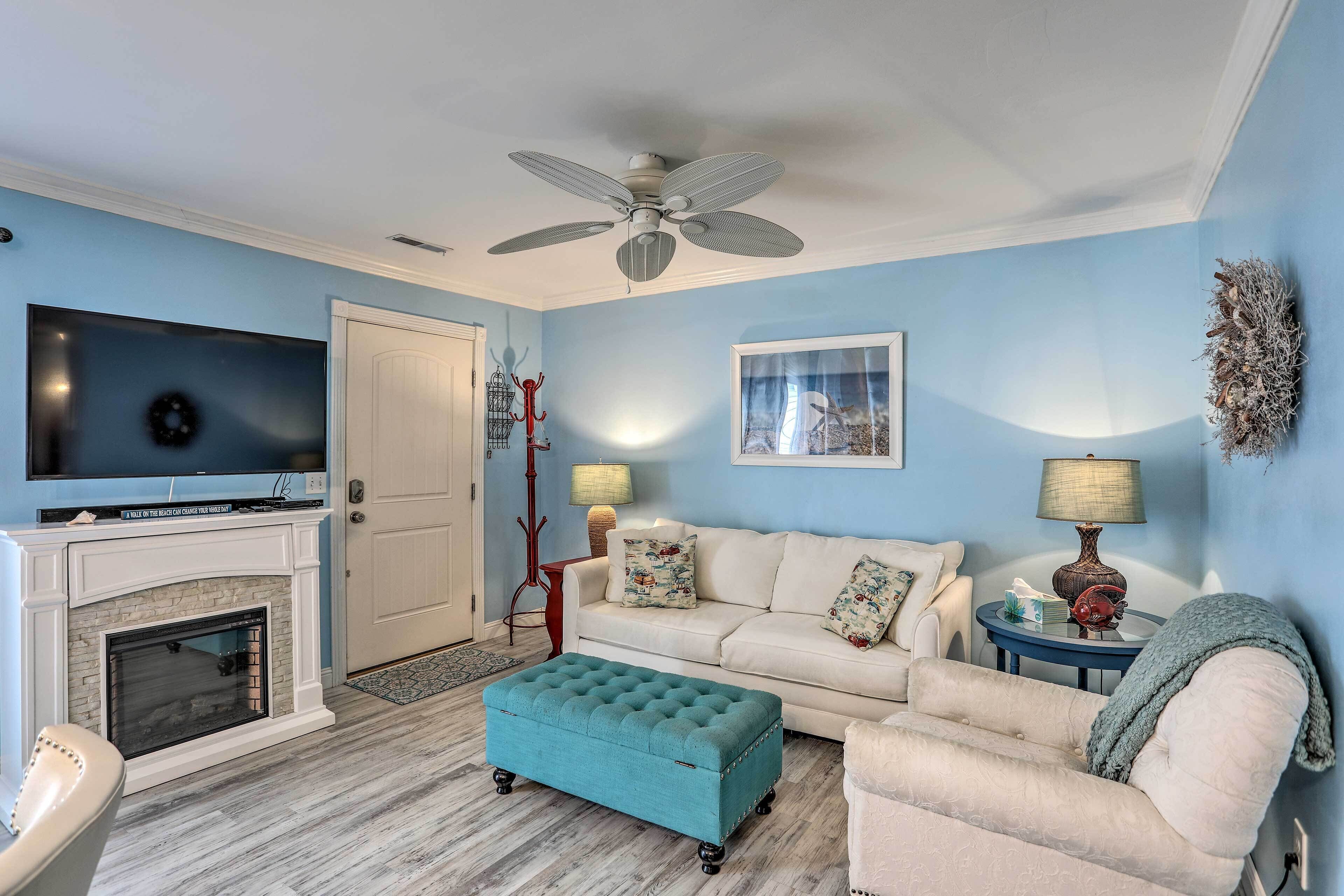 A living room with a fireplace, a sofa, a television, and a ceiling fan.