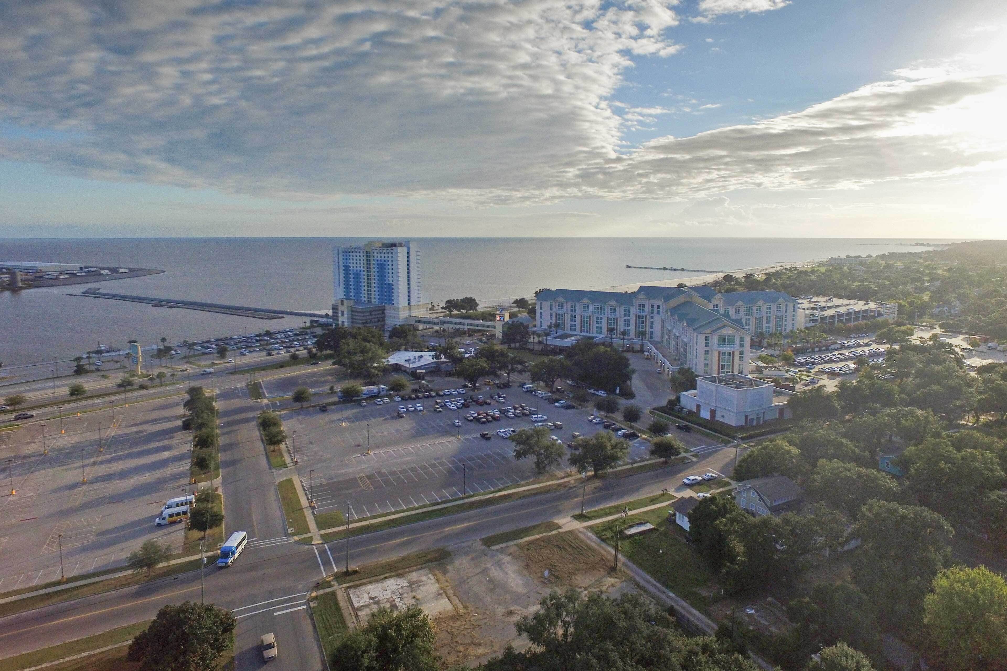 Vue aérienne d’une ville côtière avec un grand hôtel, des parkings et une marina.