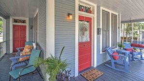 A porch with rocking chairs, a red door, and a small table with a plant. - Charming Gulfport Getaway Only 3 Blocks to Beach! (Gulfport)