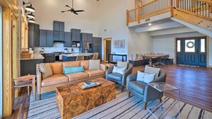 Amplia sala de estar con techo alto, vigas de madera, comedor y cocina equipada con electrodomésticos modernos.