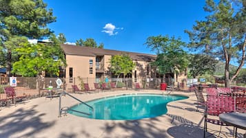 A swimming pool with lounge chairs and a building in the background.