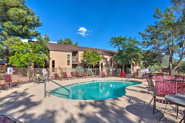 A swimming pool with lounge chairs and a building in the background.