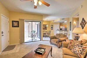 A living room with a sofa, coffee table, and a dining area with chairs and a table.