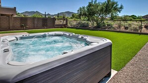 Un bain à remous dans un jardin, avec une vue dégagée sur les montagnes et une pelouse bien entretenue.