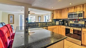 Una cocina moderna con encimeras de granito, armarios de madera, un microondas de acero inoxidable y un horno.