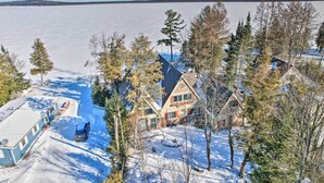 A large house with a sloped roof, surrounded by snow-covered ground and trees.