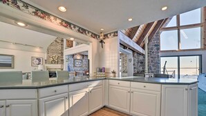 A spacious kitchen with white cabinetry, a large island, and a stone accent wall.