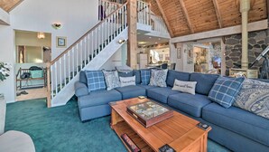 A spacious living room with a blue sectional sofa, a wooden coffee table, and a staircase leading to an upper level.