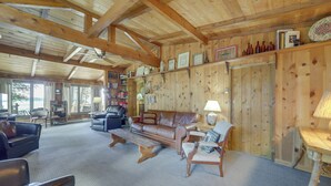 Ein gemütliches Wohnzimmer mit einem braunen Ledersofa, einem Holztisch und einem Bücherregal voller Bücher und Dekoration.