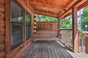A wooden porch with a bench, large windows, and a view of trees. - Cabin w/ Deck + Fireplace < 3 Mi to Dollywood! (Pigeon Forge)