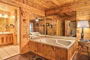 A wooden cabin bathroom with a large bathtub, wooden cabinets, a mirror, and a ceiling fan. - Cabin w/ Deck + Fireplace < 3 Mi to Dollywood! (Pigeon Forge)