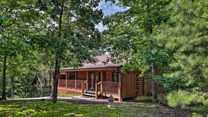 A rustic cabin with a wooden deck and a porch, surrounded by dense forest. - Cabin w/ Deck + Fireplace < 3 Mi to Dollywood! (Pigeon Forge)