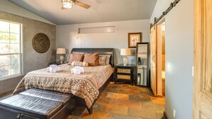 Ein Schlafzimmer mit Bett, Deckenventilator, Fenster, Nachttisch und Tür.